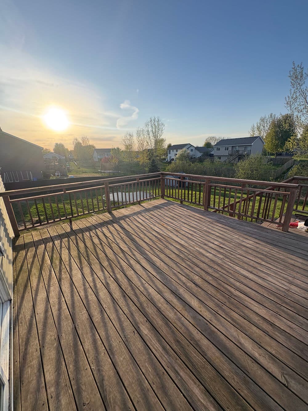 Sunset view from a spacious wooden deck overlooking a serene neighborhood landscape.